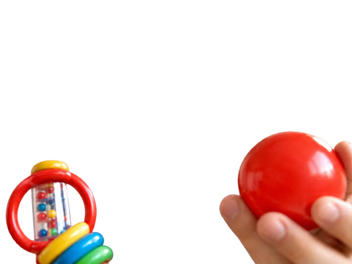 A hand holding a red ball, and a colourful rattle